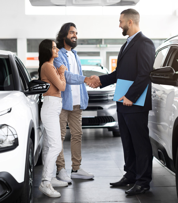 stock photo couple at car dealership shaking hands with salesperson